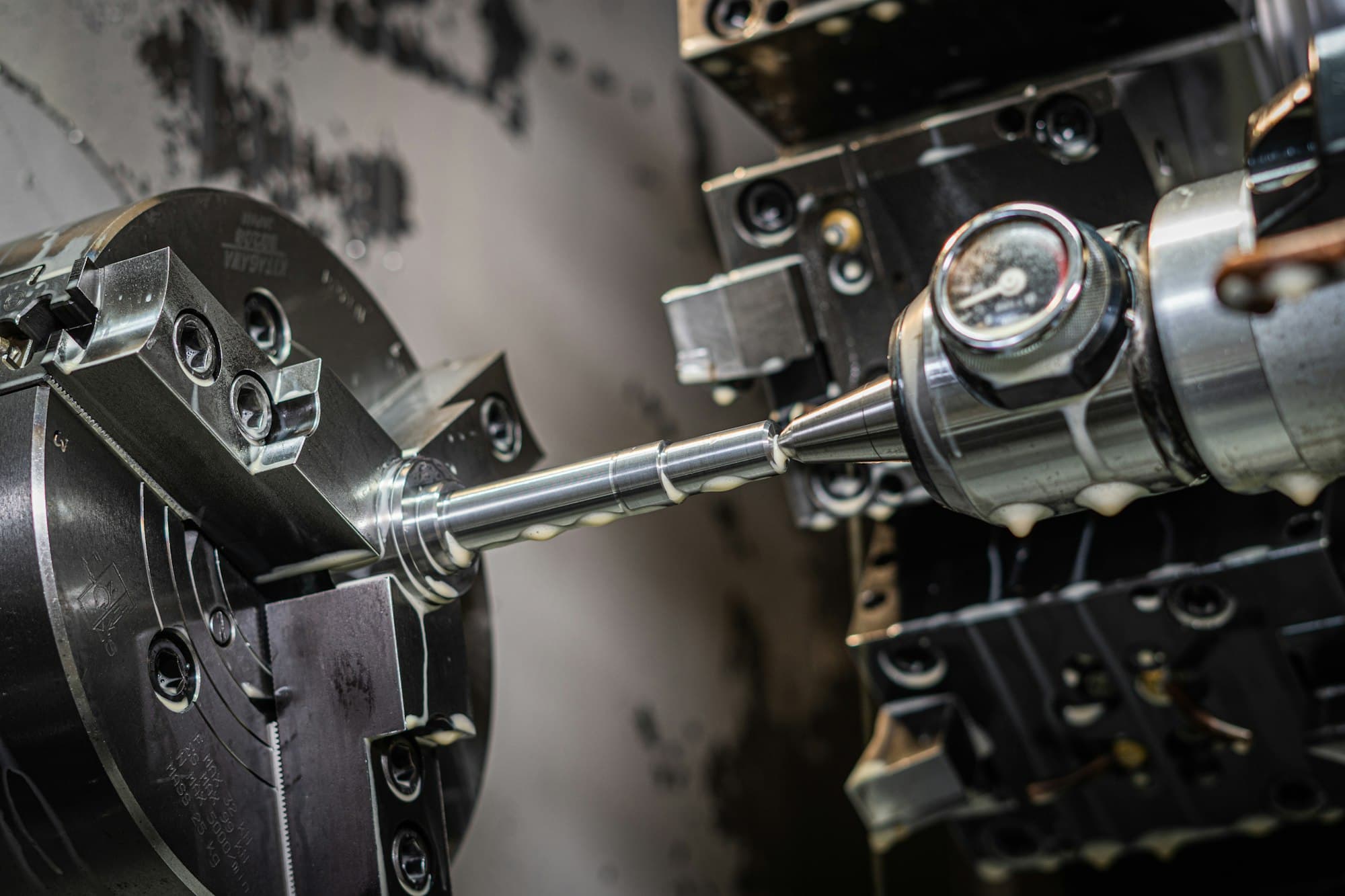 Close-up detail of precision machining equipment during a turning operation, showing coolant and tooling in contact with a metal workpiece.