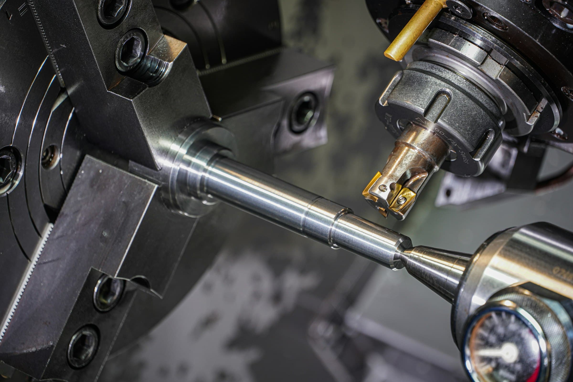 Close-up of a precision CNC lathe machining a metal shaft, with a cutting tool engaged against the rotating part.